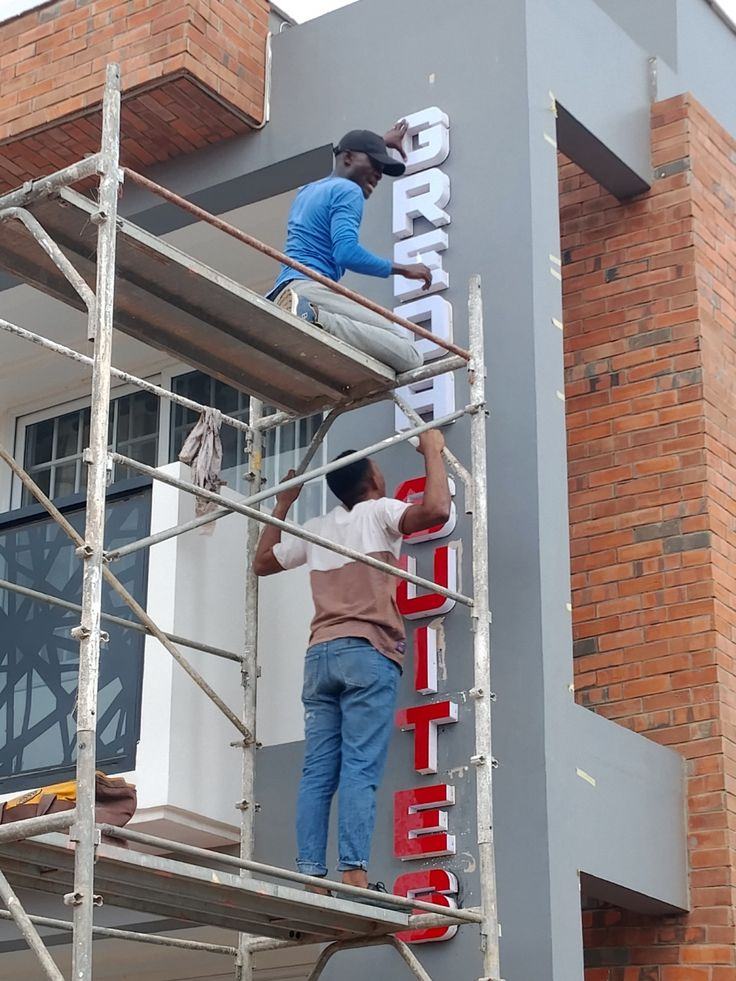 Vertical 3D lettering being installed on a suites building